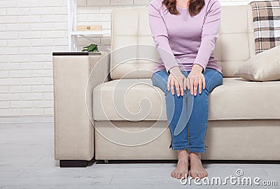 Cropped image of female sore knee. Woman at home background. Copy space and mock up. Warm Ñ„Ñ‚Ð² Ñ€ÑƒÑ„ÐµÑˆÑ‚Ð¿ floor Stock Photo